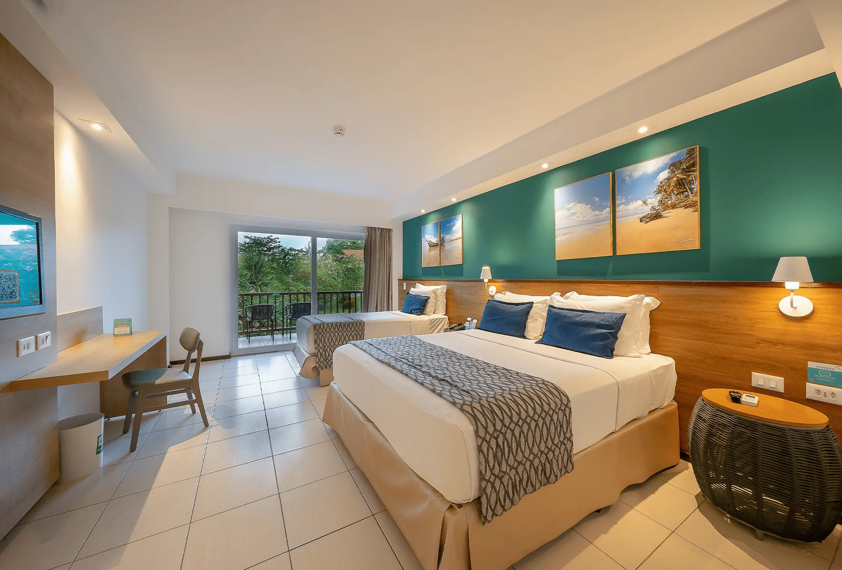 Apartamento Standard do Salinas Maceió com cama casal e cama solteiro, varanda com vista pra área verde, decoração praiana com parede verde.