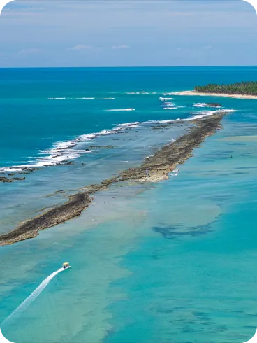 Vista aérea de recifes de corais com águas azul-turquesa e barcos navegando no cenário.