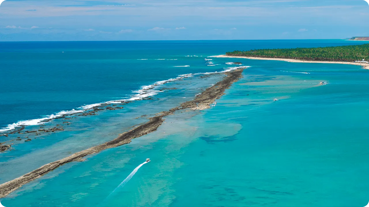 Vista aérea de recifes de corais com águas azul-turquesa e barcos navegando no cenário.