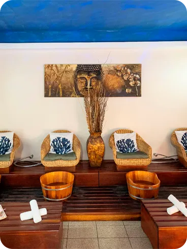 Spa room for foot baths with wicker armchairs, wooden buckets, decorative pillows, blue ceiling and a peaceful environment with soft lighting, ideal for relaxing therapies