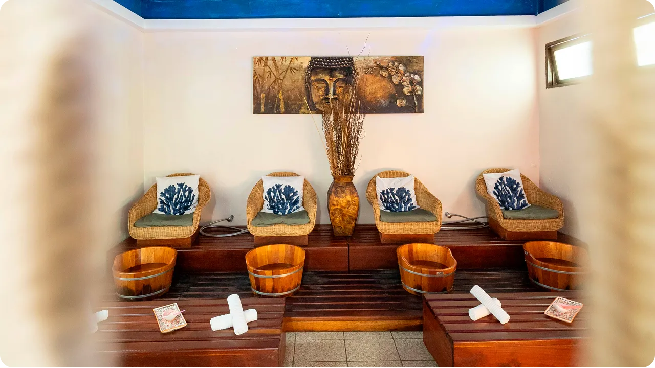 Spa room for foot baths with wicker armchairs, wooden buckets, decorative pillows, blue ceiling and a peaceful environment with soft lighting, ideal for relaxing therapies