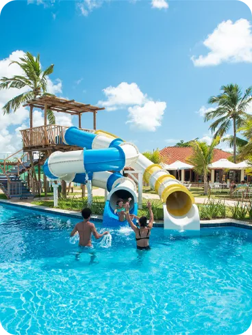 Crianças e adultos se divertem em toboáguas na piscina do resort.