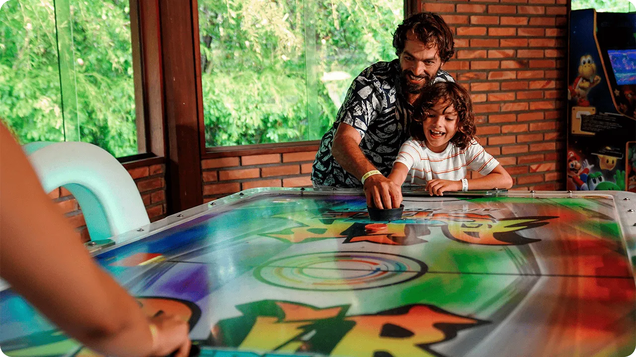 Father and son playing air hockey in the Salinas Maragogi recreation area