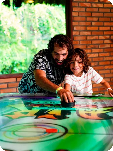 Father and son playing air hockey in the Salinas Maragogi recreation area