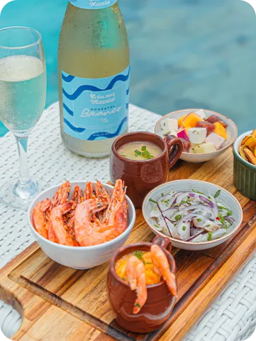 Taça de espumante com vinho moscatel ao lado de petiscos como camarão, frios e cebola temperada, à beira da piscina