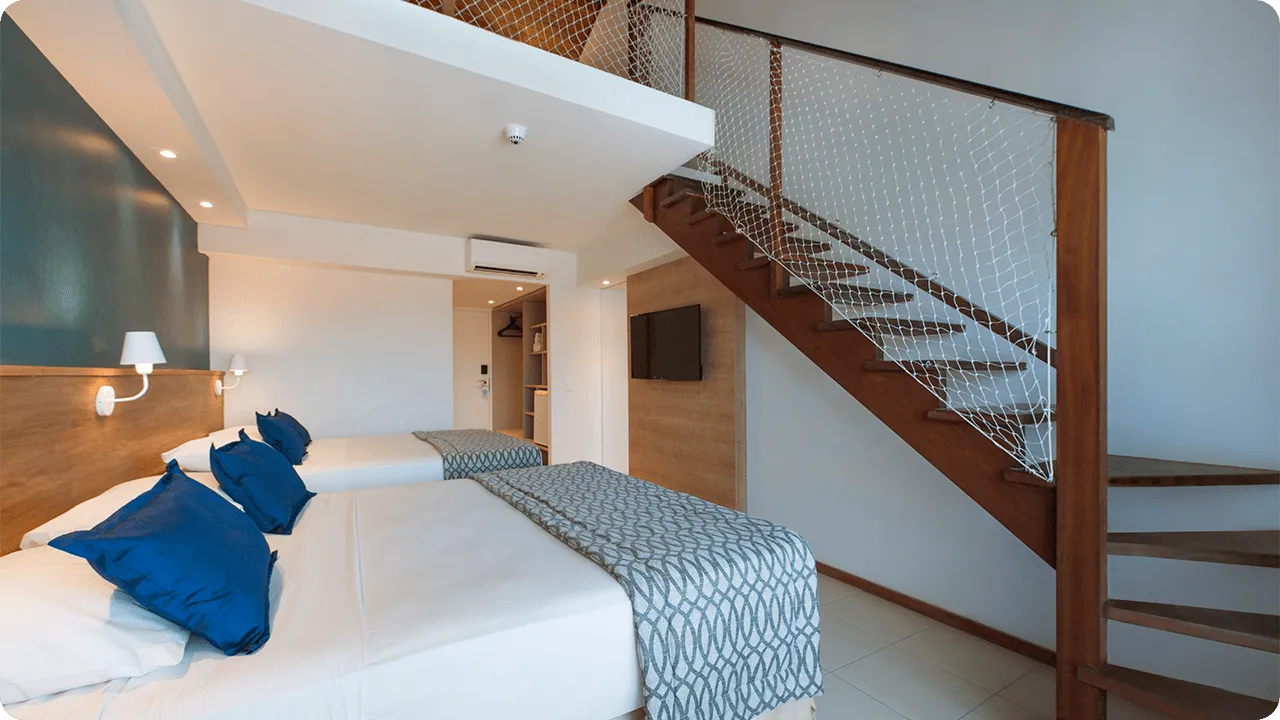 Two single beds arranged side by side like a double bed, with two lamps, one for each side of the bed, in front of the cable TV and air conditioning, next to the closet and bathroom on the upper floor.