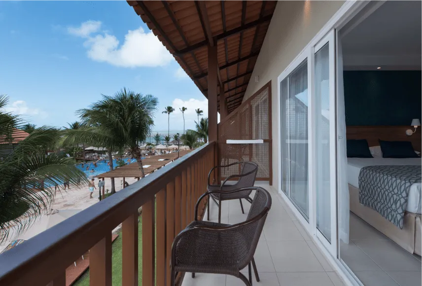 Balcón de la acomodación superior, con dos sillas y vista para una piscina.