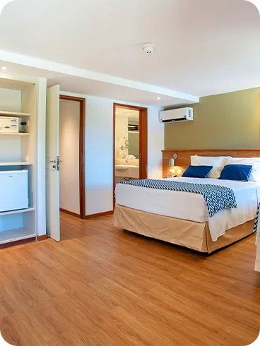 Otra configuración de la Suite Familia, alojamiento en el Salinas Maragogi Resort Todo Incluido, con una cama queen size, una cama individual, armario, minibar, lámparas, decoración en madera, una imagen de una balsa en el río Maragogi y puerta al baño.