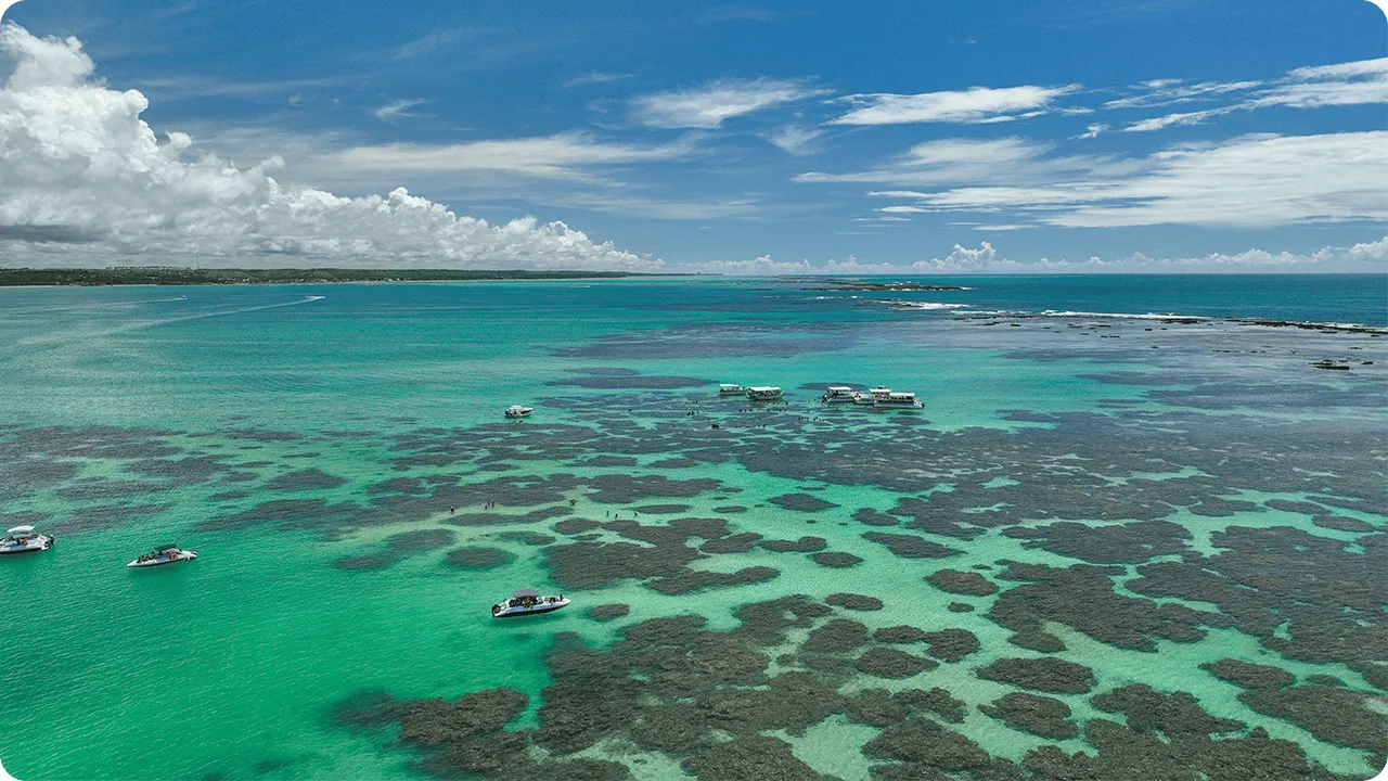 Piscinas naturais das Galés de Maragogi vistas do alto, com lanchas e catamarãs ancorados sobre águas transparentes e corais, destino imperdível no litoral norte de Alagoas conhecido como o Caribe brasileiro