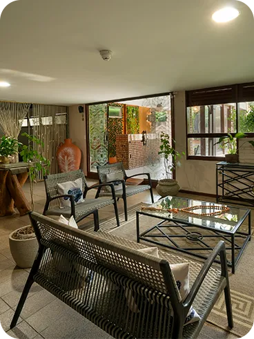 Spa waiting room with comfortable armchairs, decoration with natural plants, soft lighting and a cozy atmosphere overlooking the landscaped outdoor area.