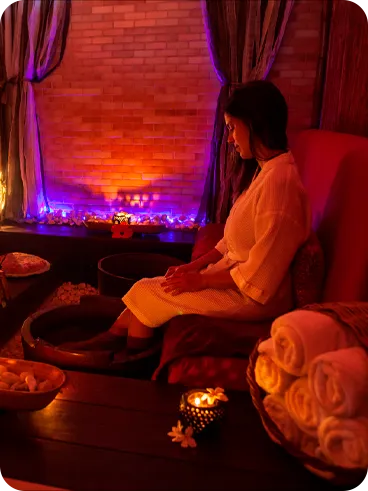 Mulher relaxando com pedilúvio em spa decorado com iluminação suave e velas aromáticas.