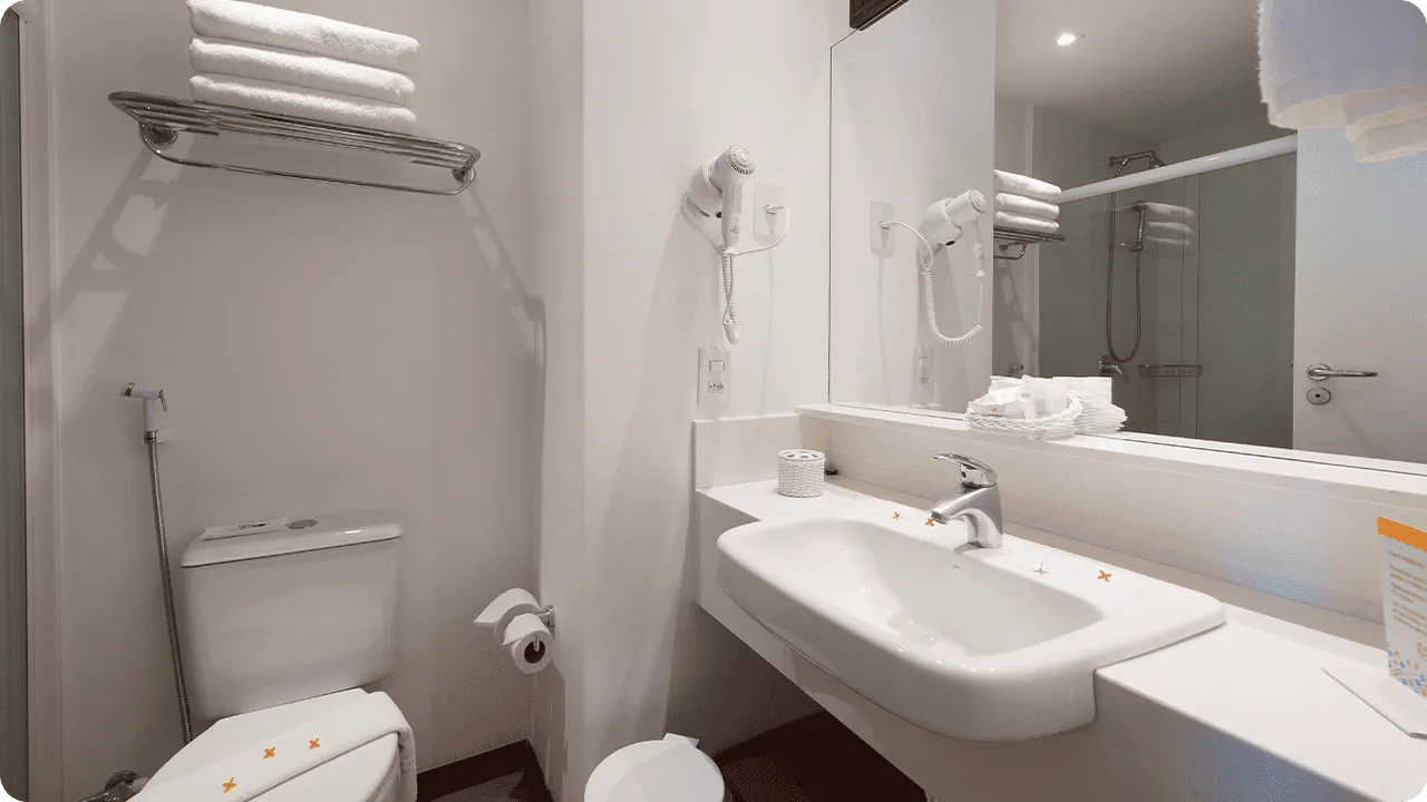 Banheiro da acomodação Praia Frente Mar, com áreas sanitárias e para banho, amenities O Boticário, pequeno varal, toalhas e secador de cabelo.