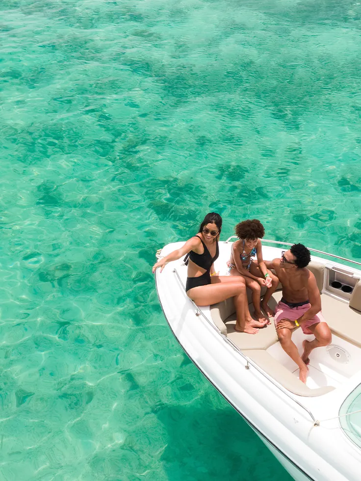 Família aproveitando passeio de lancha sobre águas cristalinas nas piscinas naturais de Maragogi, cenário paradisíaco ideal para turismo em família no litoral de Alagoas.