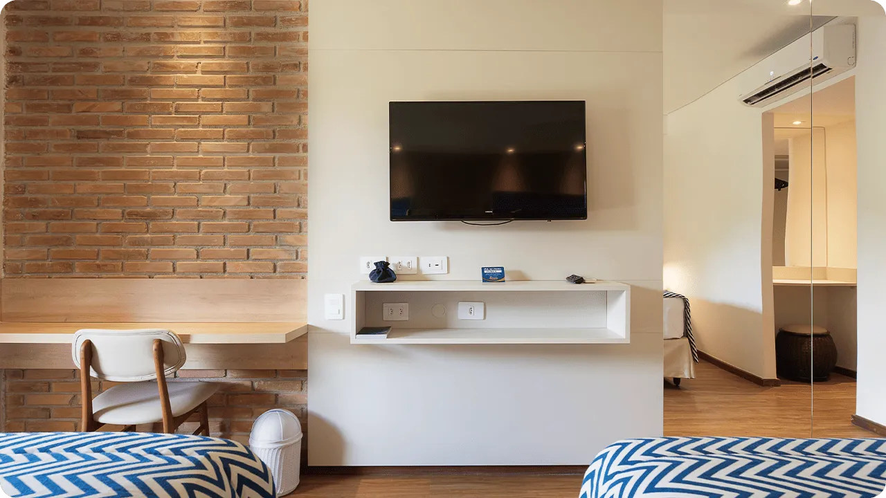 Detalles de los elementos que componen el alojamiento Playa Jardín, con TV por cable, paneles de madera, espejos, camas, mesa y silla.