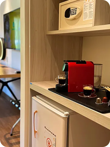 Detalles de la Estándar Vitória-Régia, una de las habitaciones del Salinas Maragogi All Inclusive Resort, con cama queen size, mesa y silla con espejo luminoso, TV por cable, baño y armario, minibar y caja fuerte digital.