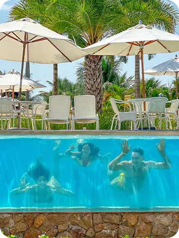 Família se divertindo na piscina com uma vista única através de um vidro subaquático.