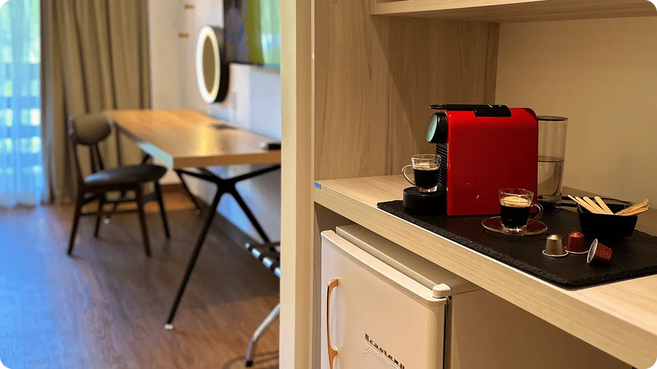 Detalles de la Estándar Vitória-Régia, una de las habitaciones del Salinas Maragogi All Inclusive Resort, con cama queen size, mesa y silla con espejo luminoso, TV por cable, baño y armario, minibar y caja fuerte digital.