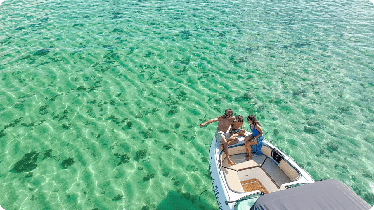 Família aproveitando passeio de lancha sobre águas cristalinas nas piscinas naturais de Maragogi, cenário paradisíaco ideal para turismo em família no litoral de Alagoas.