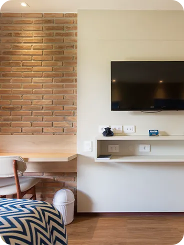 Detalles de los elementos que componen el alojamiento Playa Jardín, con TV por cable, paneles de madera, espejos, camas, mesa y silla.