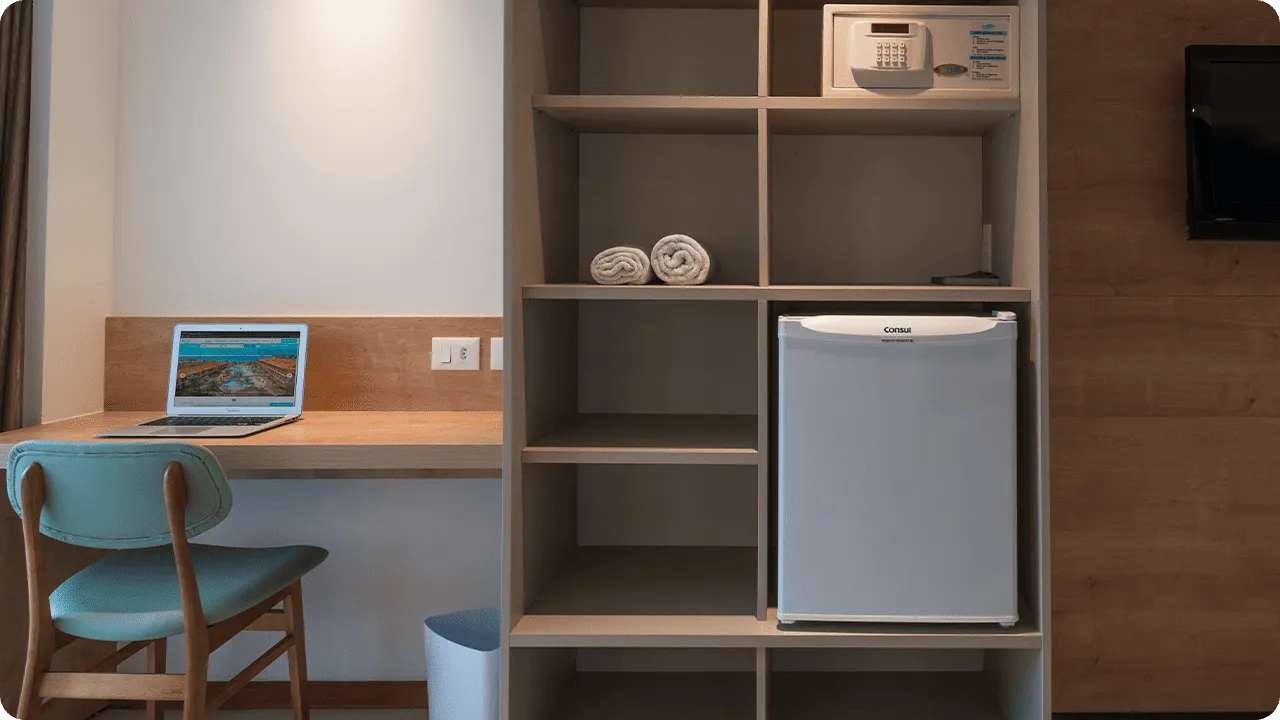 Itens padrão presente nas acomodações Standard, com frigobar, cofre digital, roupeiro e mesa com cadeira.