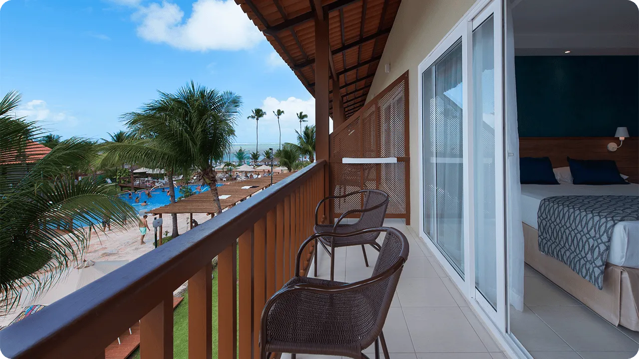 Deluxe room balcony, with two chairs and a pool view.