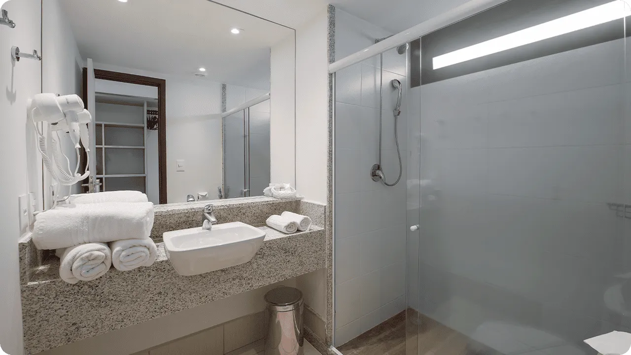 Deluxe Room Bathroom, with a bathroom and temperature-adjustable shower, sink, towels, hairdryer, and O Boticário amenities.