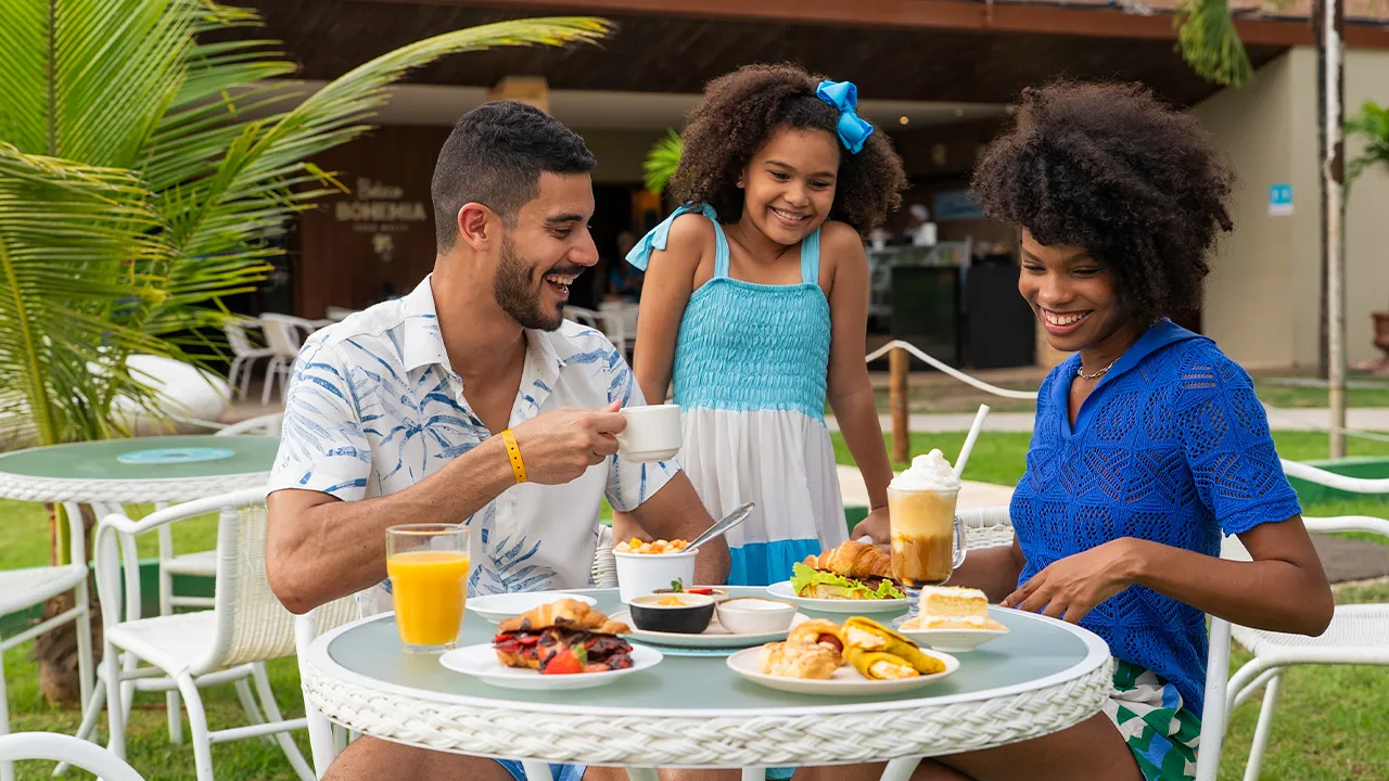 Família reunida em mesa no jardim aproveitando o café da manhã no resort