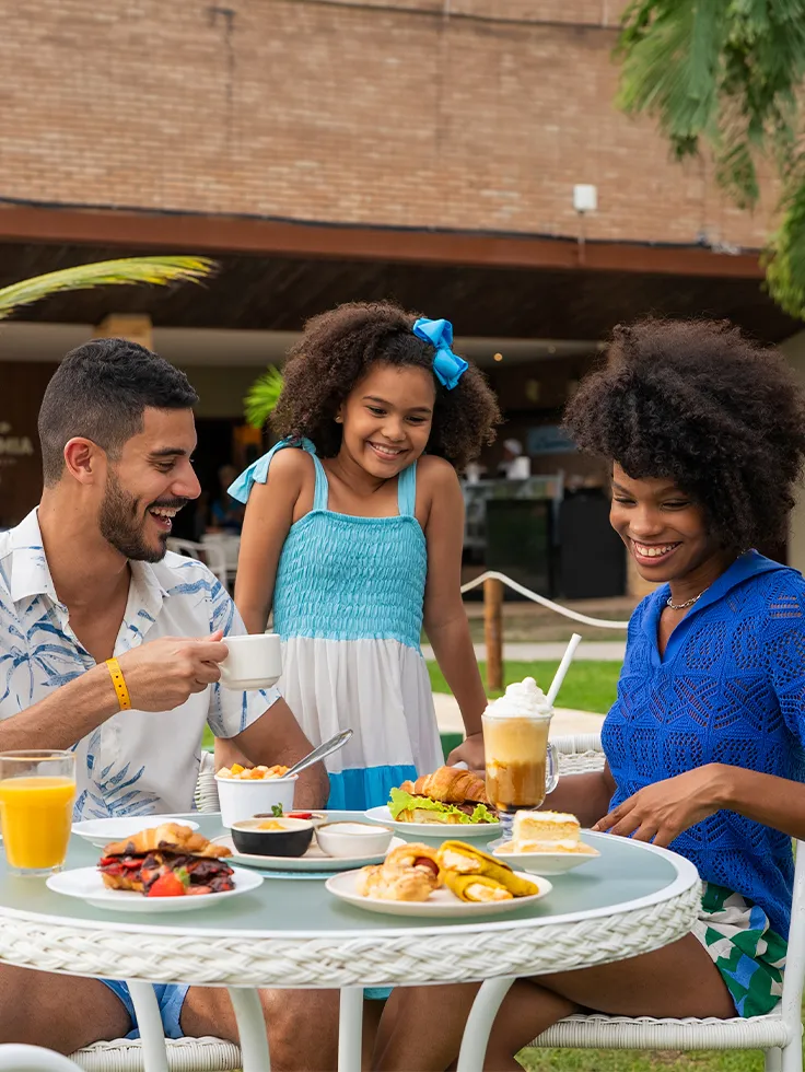 Família reunida em mesa no jardim aproveitando o café da manhã no resort
