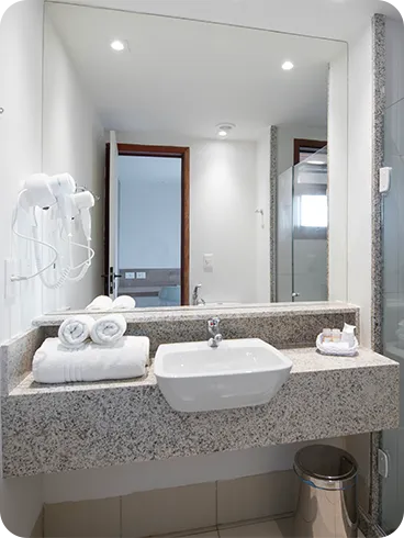 Banheiro da acomodação Standard, contendo área pra banho, instalações sanitárias, chuveiro com regulação de temperatura, decoração, amenities O Boticário, toalhas, grande espelho e secador de cabelo.