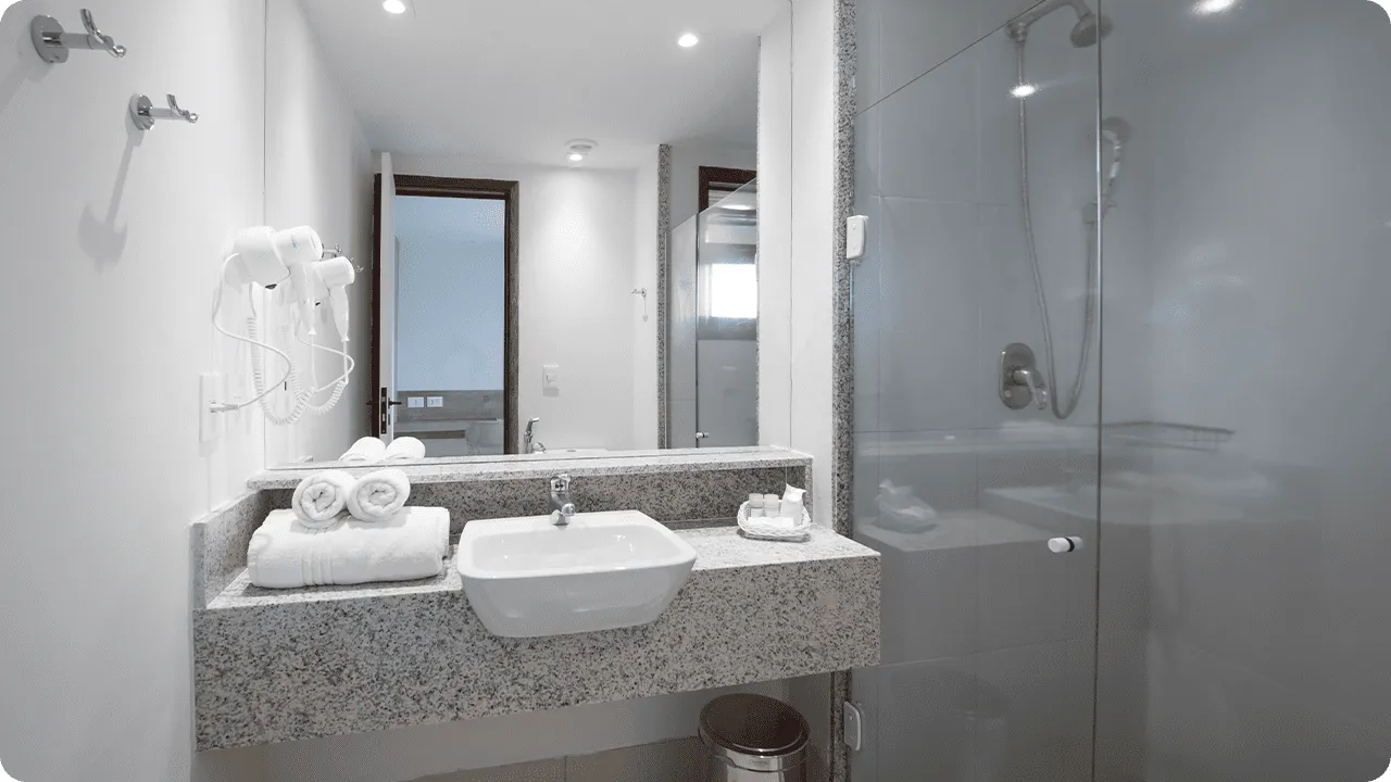 Banheiro da acomodação Standard, contendo área pra banho, instalações sanitárias, chuveiro com regulação de temperatura, decoração, amenities O Boticário, toalhas, grande espelho e secador de cabelo.