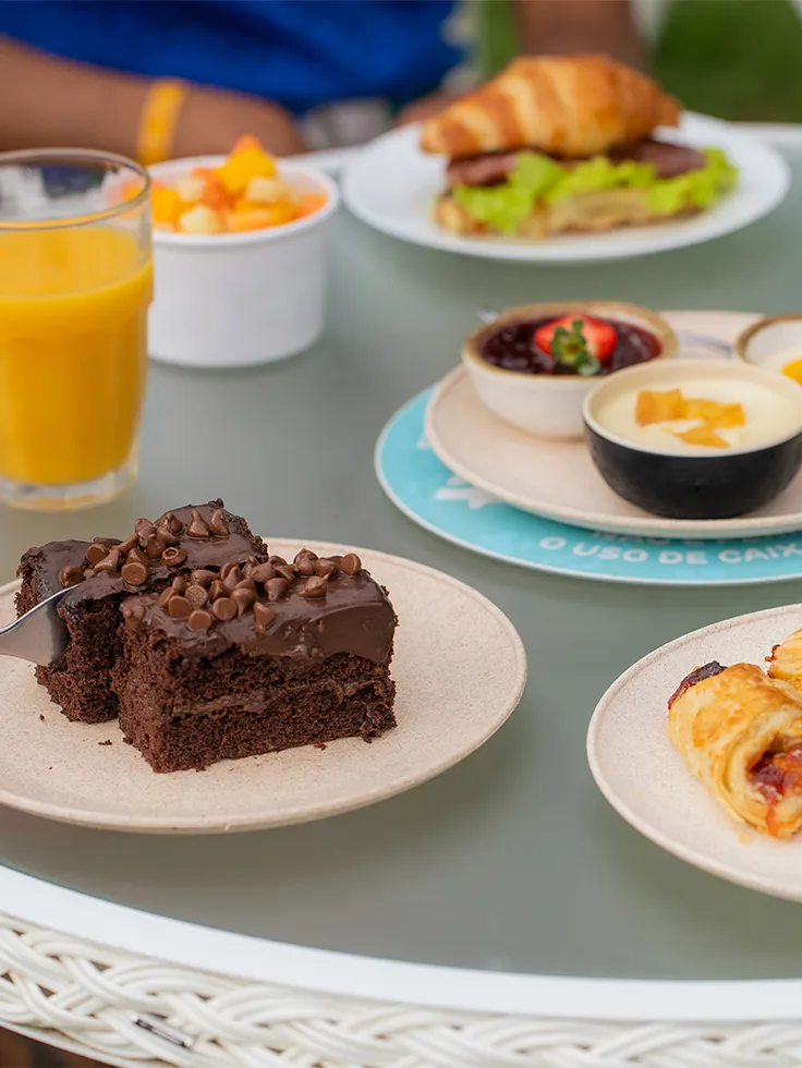 Brownie de chocolate servido com café cremoso, salada de frutas e alguns salgados no resort All Inclusive