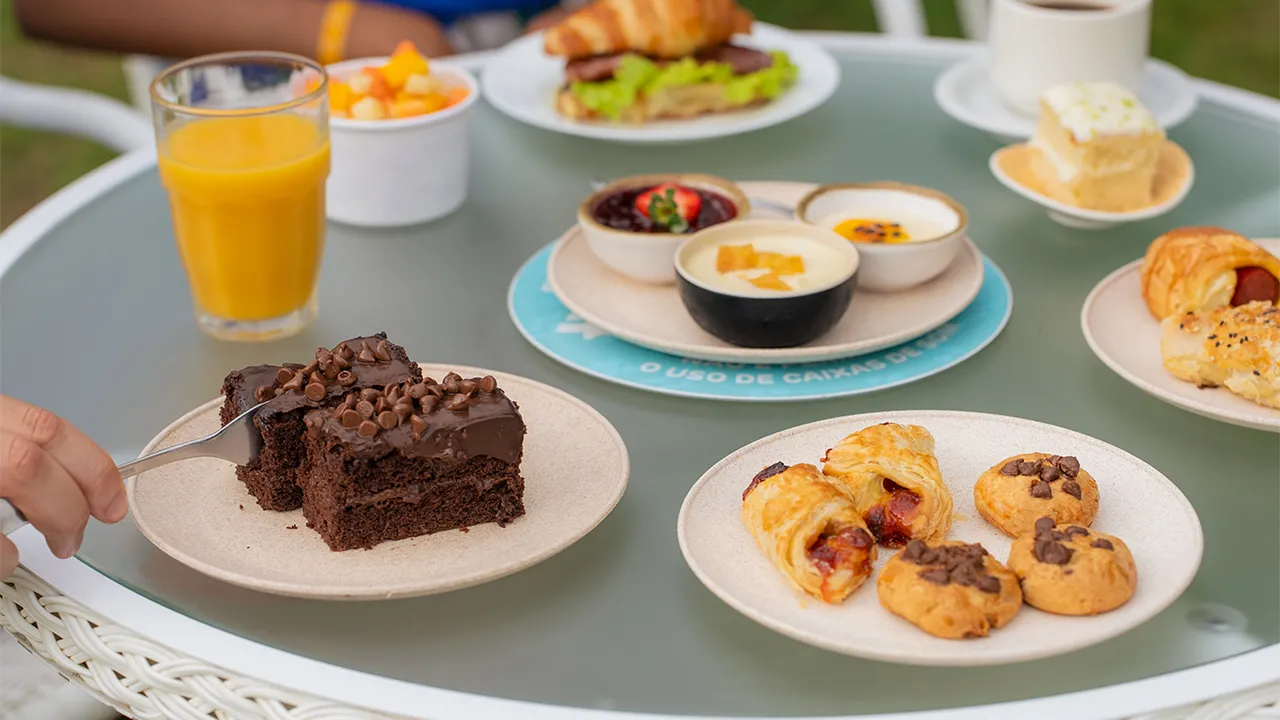 Brownie de chocolate servido com café cremoso, salada de frutas e alguns salgados no resort All Inclusive