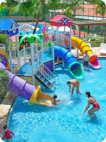 Crianças e adultos brincando em piscina com escorregadores coloridos no resort
