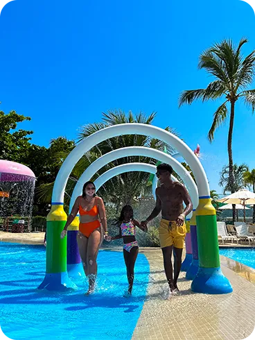 Family having fun in the children's pool area, with toys that shoot colorful water jets