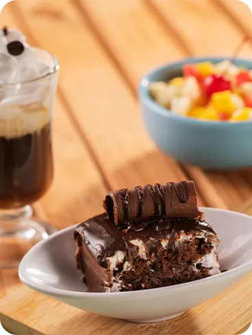 Brownie de chocolate servido com café cremoso e salada de frutas no resort All Inclusive