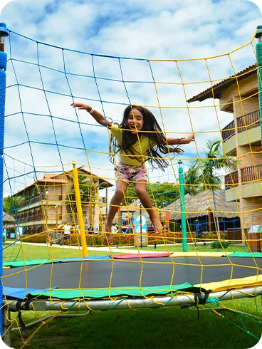 Criança pulando em cama elástica no resort durante um dia ensolarado