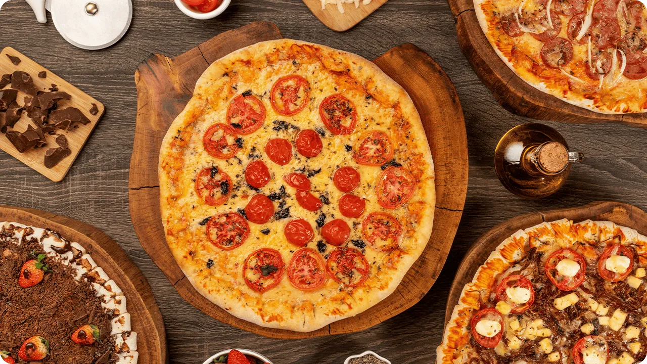Diferentes sabores de pizza, incluindo opções salgadas e doce, servidas no sistema All Inclusive