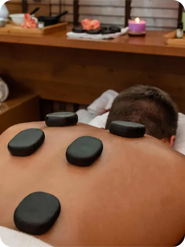 Pessoa recebendo massagem terapêutica com pedras quentes nas costas