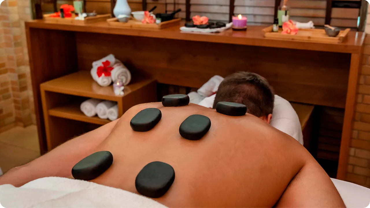 Pessoa recebendo massagem terapêutica com pedras quentes nas costas