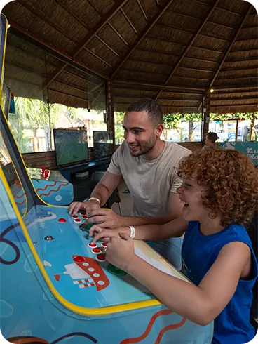 Pai e filho jogando juntos em fliperama no resort
