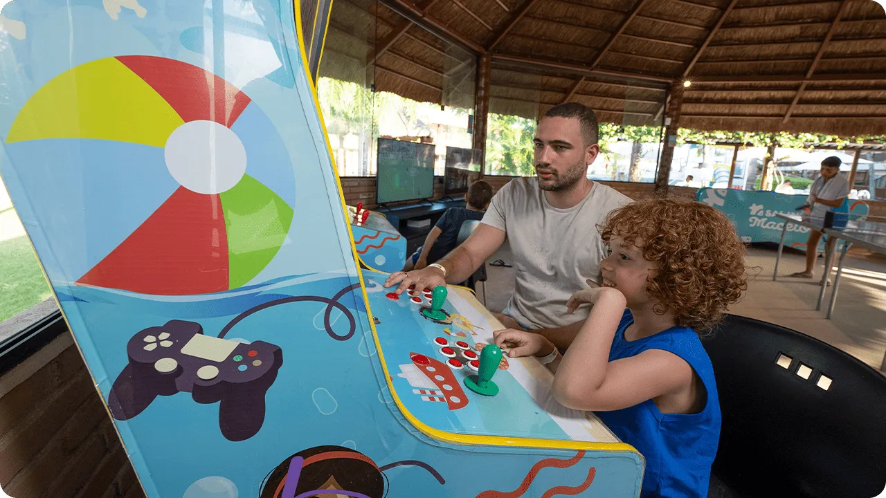 Pai e filho jogando juntos em fliperama no resort