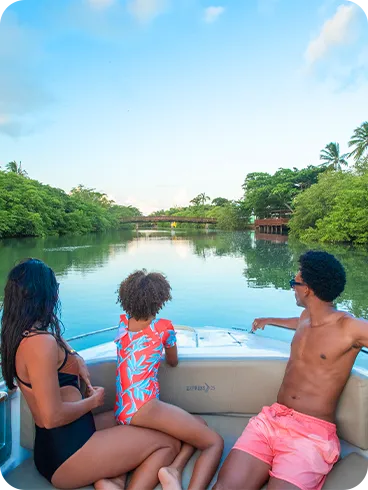 Família aproveitando passeio de lancha pelo rio Maragogi, admirando a paisagem natural.