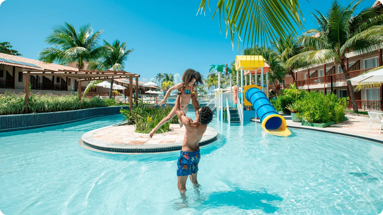 Pai brincando com filha na piscina infantil do resort