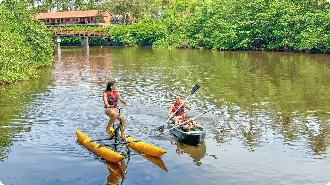 Família aproveitando atividades aquáticas no rio Maragogi, com caiaque e bicicleta aquática.