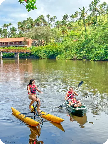 Família aproveitando atividades aquáticas no rio Maragogi, com caiaque e bicicleta aquática.