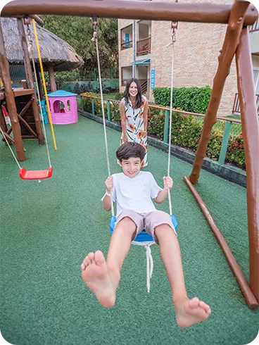 Crianças brincando no parquinho do resort com balanços e brinquedos