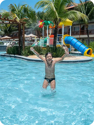 Criança se divertindo e pulando na piscina infantil do resort