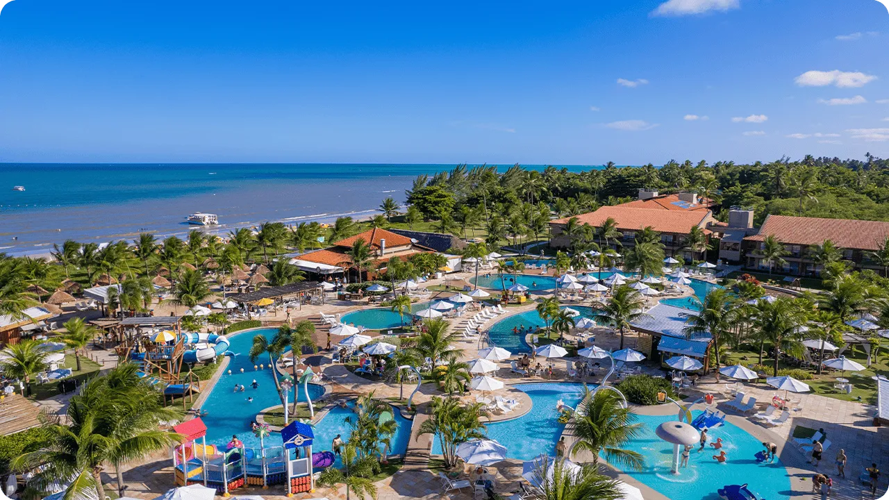 Aerial view of the beachfront Salinas Maragogi resort with pools, a children's area, and coconut trees.