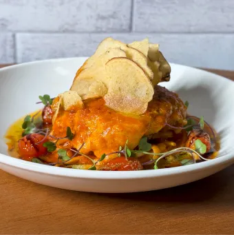 Prato gourmet de jantar com filé de peixe ao molho de tomate, servido sobre massa com tomatinhos e finalizado com chips crocantes de batata e microverdes.