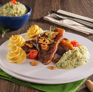 Prato com carne grelhada, arroz verde, purê de batata e taça de vinho tinto